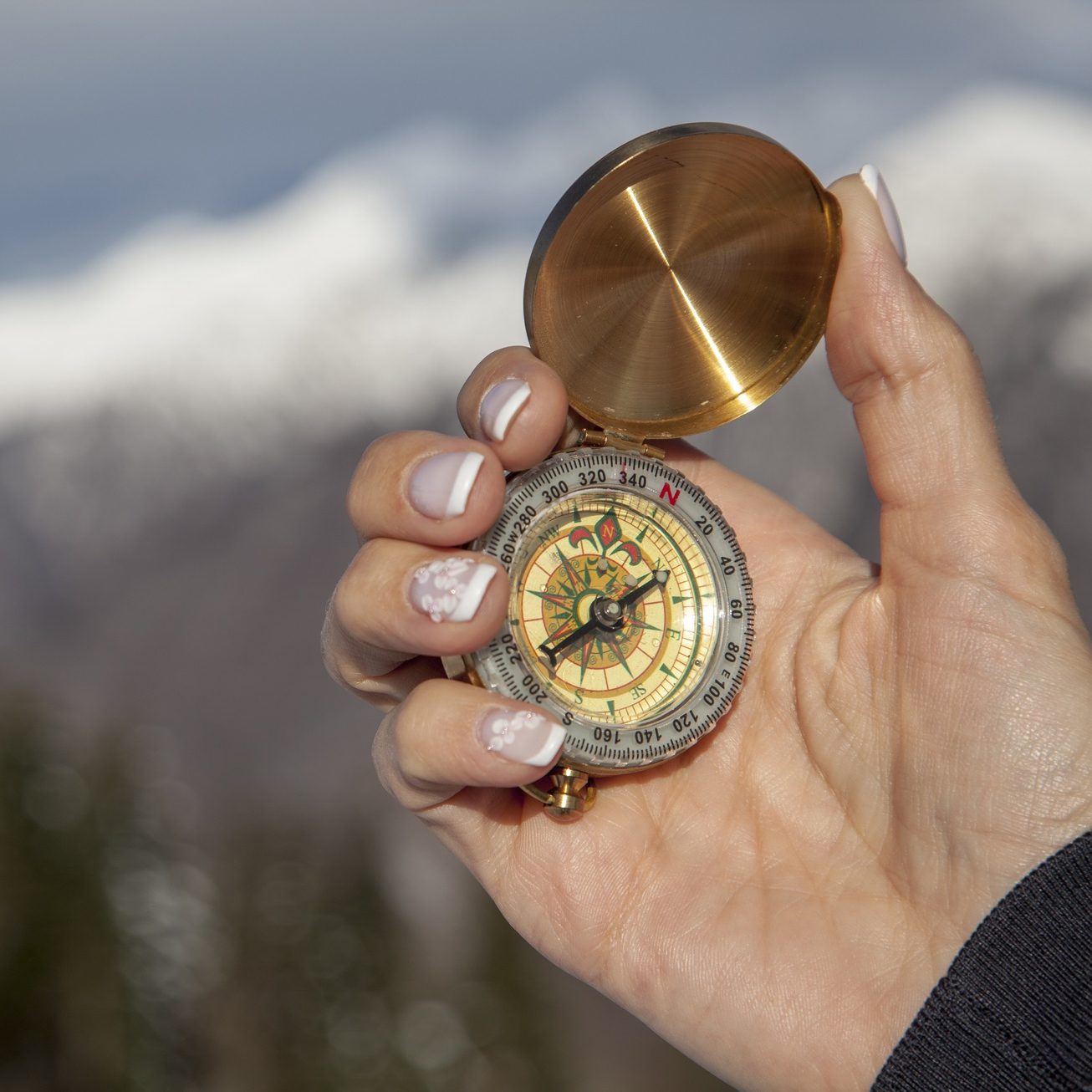 A hand holding a metal compass