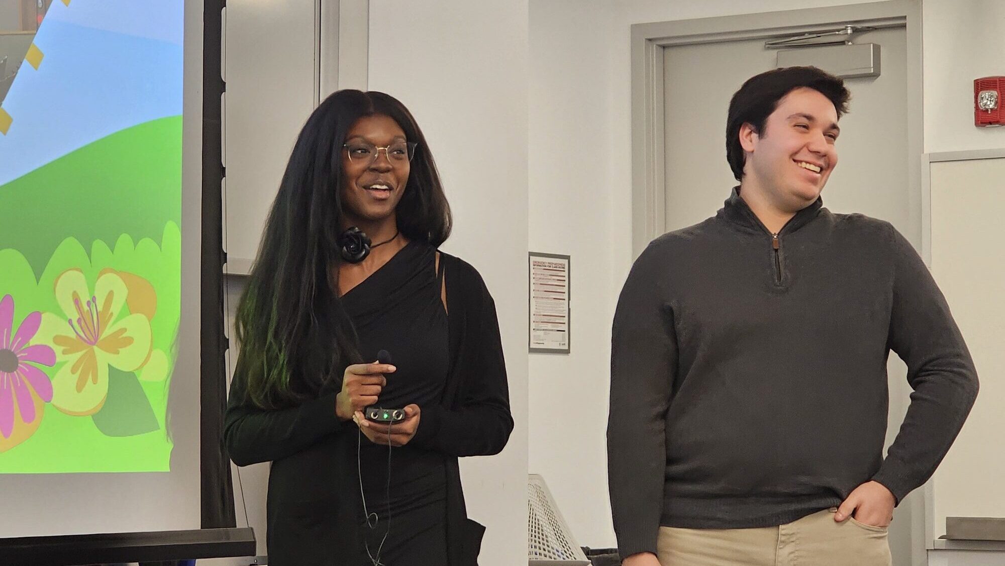 two students smile as they present in a classroom