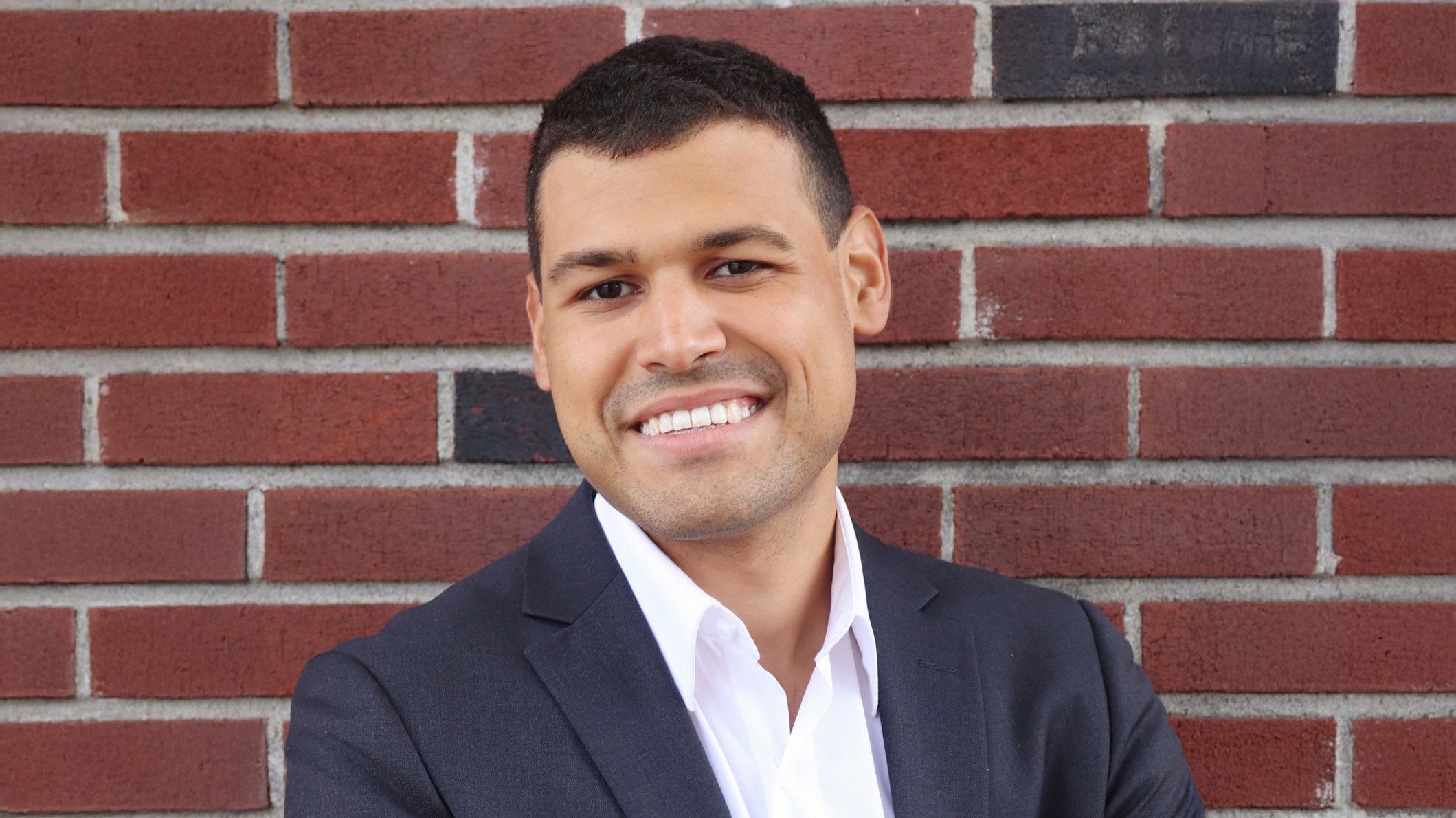 Professor Nick Rivera stands in front of a brick wall