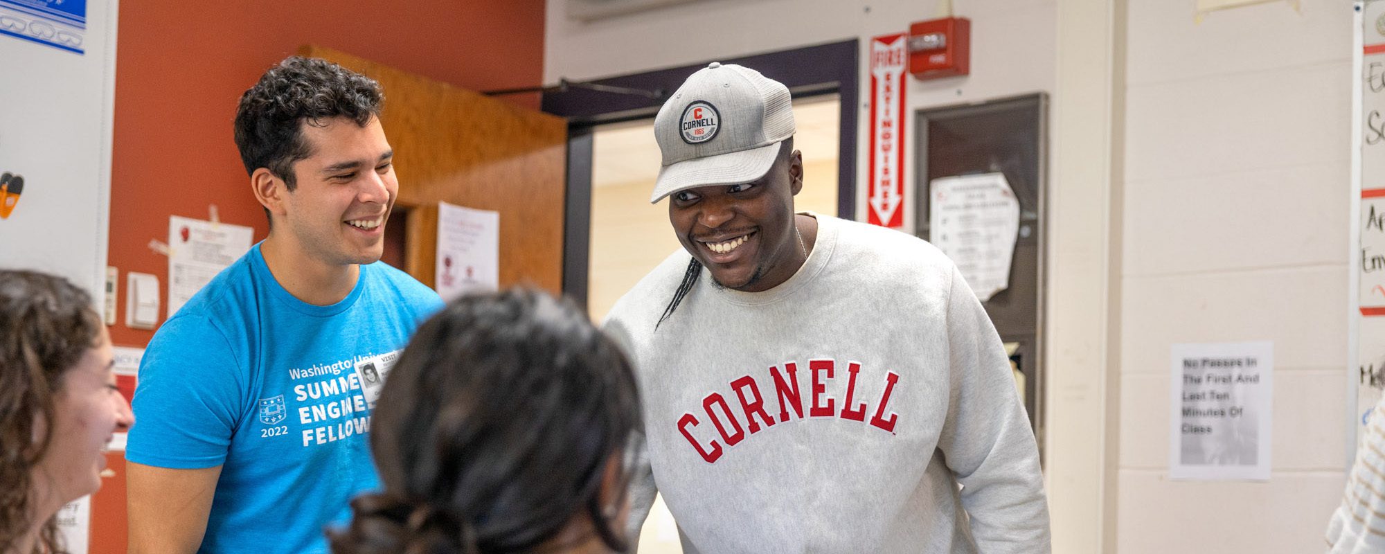 Masters of Engineering students Sruti Yanamandra, ’23, stripped shirt, Ini Adeleye, ’23, Cornell sweatshirt, and Nathaniel Garcia, ’23, blue shirt, give a presentation to students at Geneva High School on the Internet of Things on Thursday, May 11, 2023.