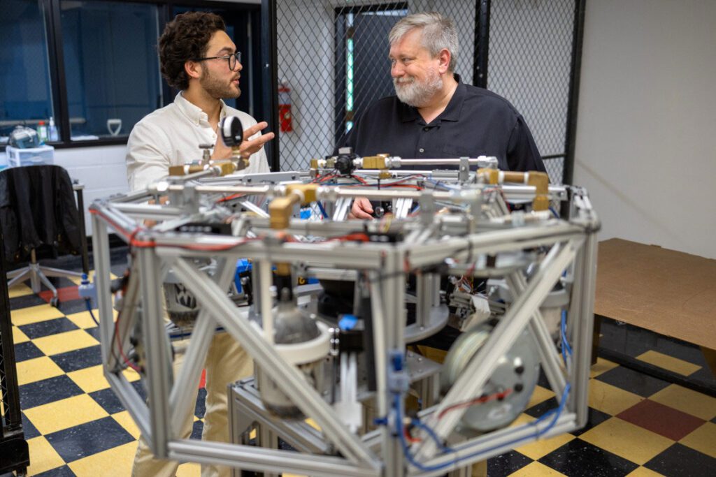 Mason Peck works with student in space lab