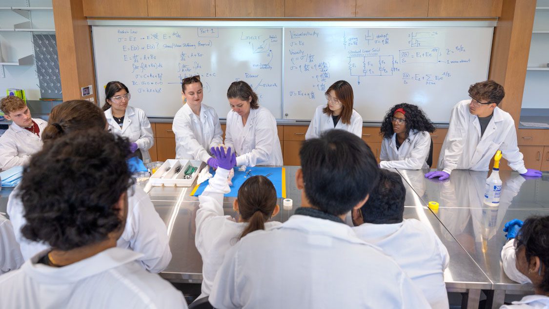 Students in front of whiteboard with equations present research