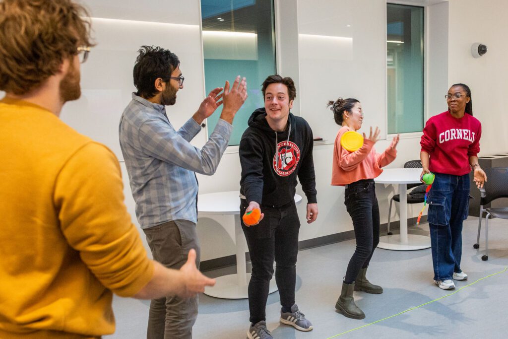 Students smile and laugh while passing juggling ball