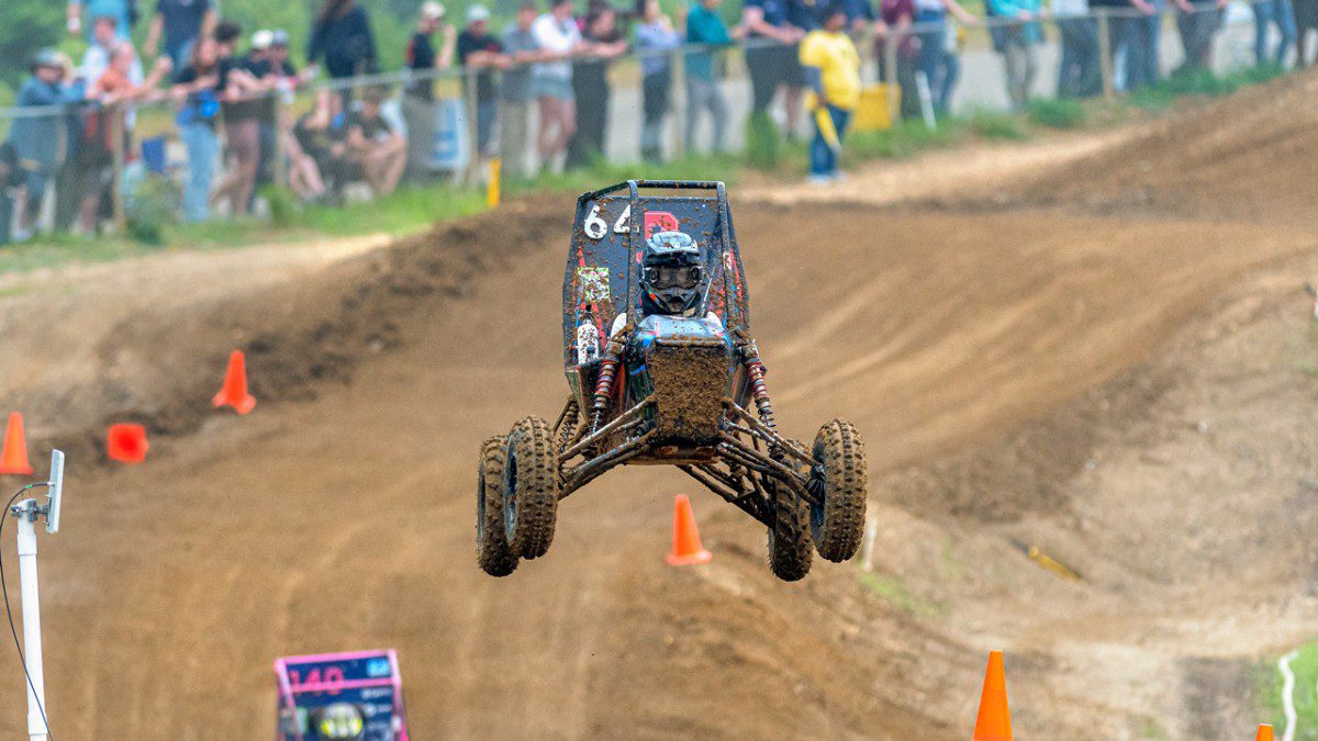 an airborne baja racing vehicle over a dirt track