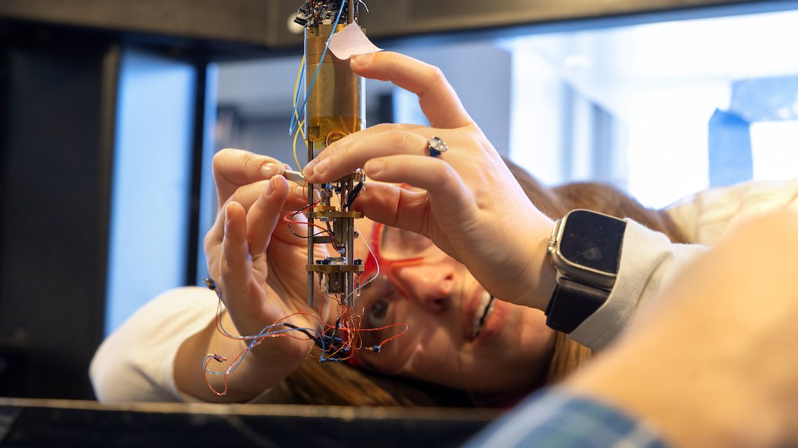 student looks closely at a hanging device
