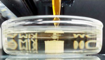 a printer head prints a square object in liquid