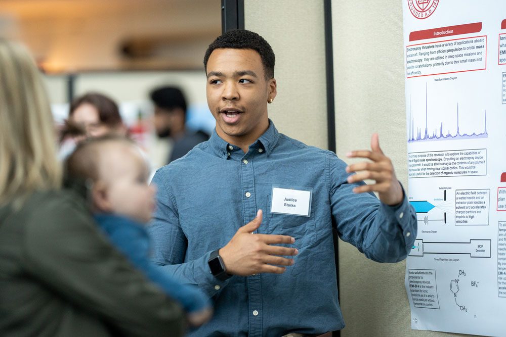 Justice Starks discusses poster presentation with onlookers