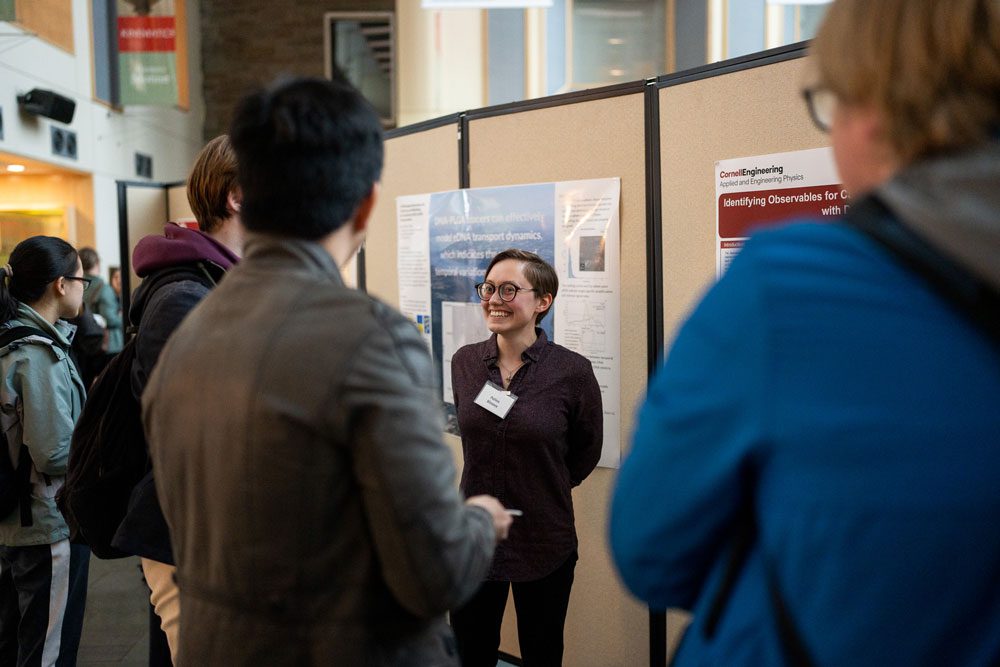 Student smiles at onlookers during presentation of poster