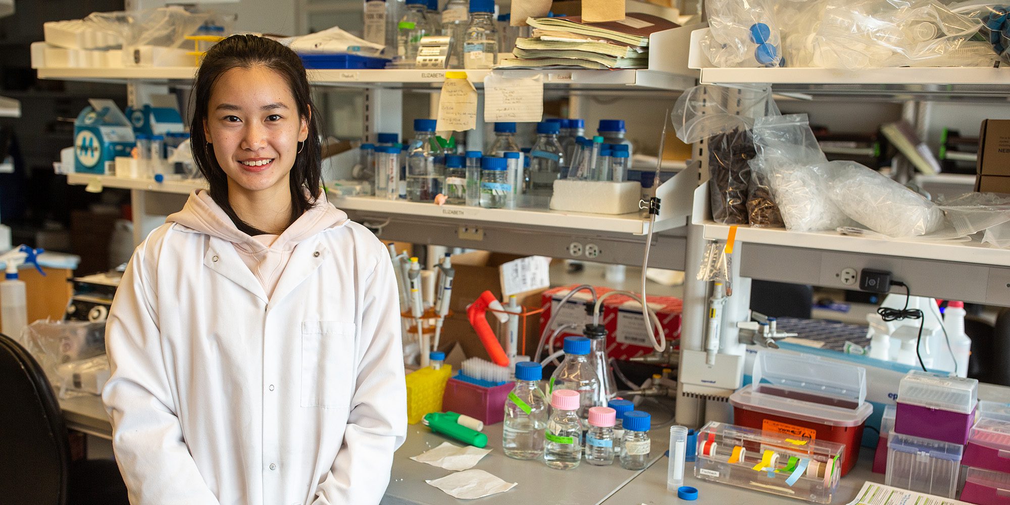 Undergraduate researcher, Yiwei stands in the lab.