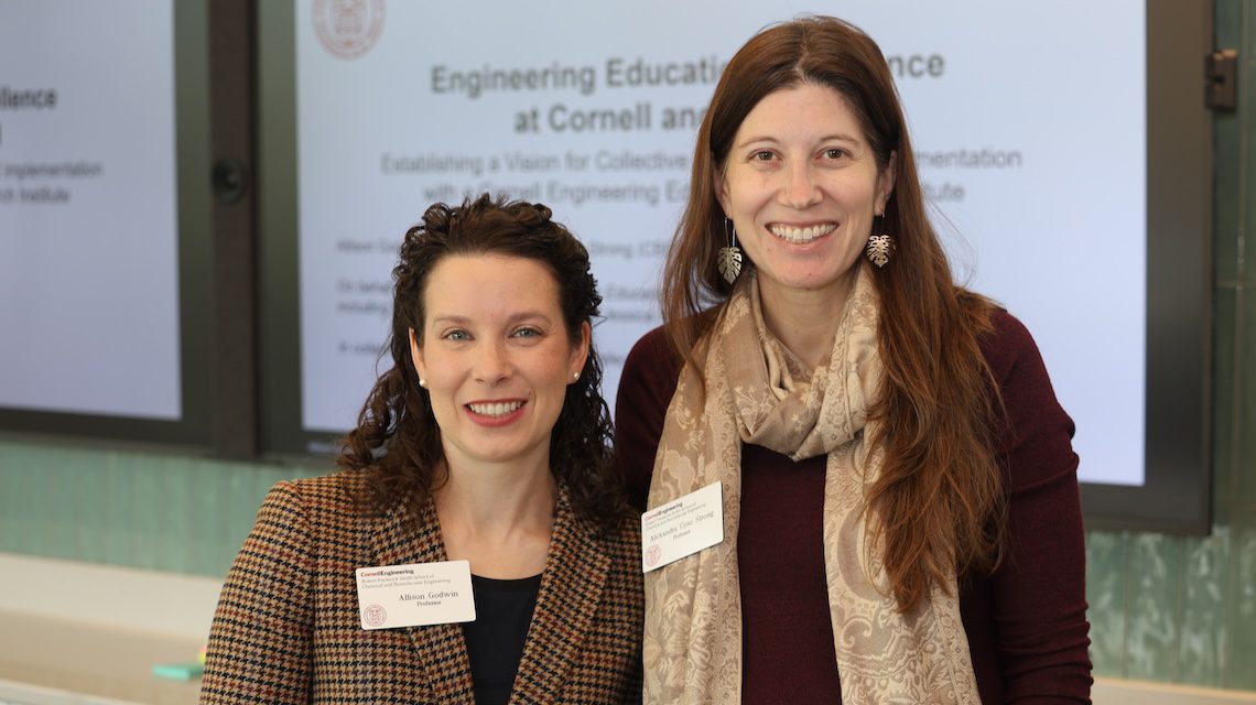 two women stand with powerpoint presentation in the background
