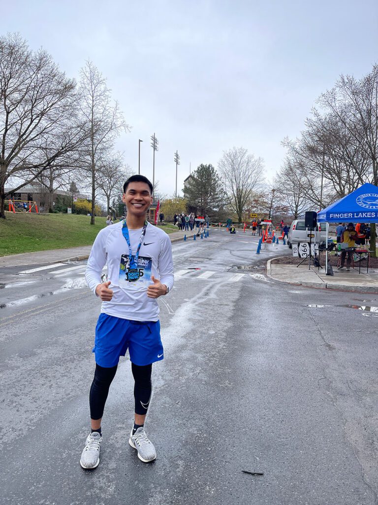 Marcus Gamboa outside in running gear and smiling brightly after finishing his first 10K in Spring 2025.