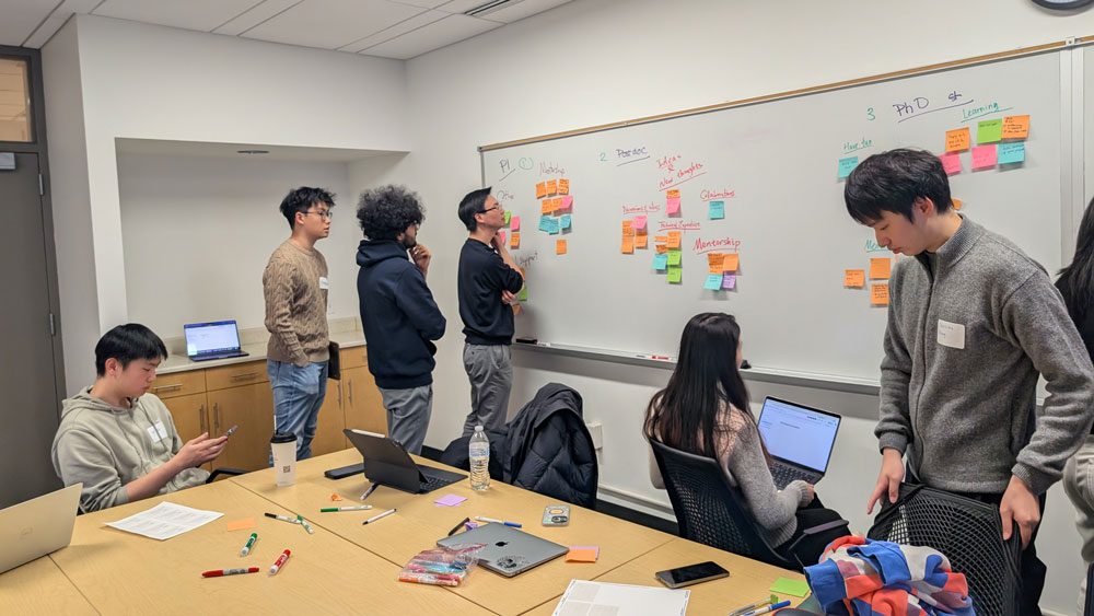 Students think together looking at sticky notes on whiteboard