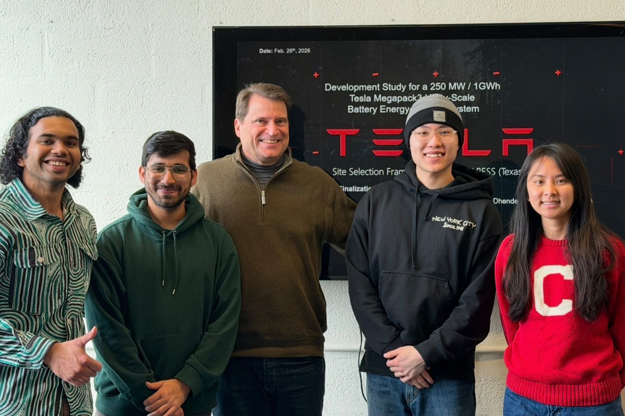 M.Eng. project team students Siddhant Dhende, Sreekar Mukkamala, Chia-Hung (Alex) Liu, and Yi-Hsuan (Sharon) Chen stand with professor Brian Bauer in front of Tesla project screen.