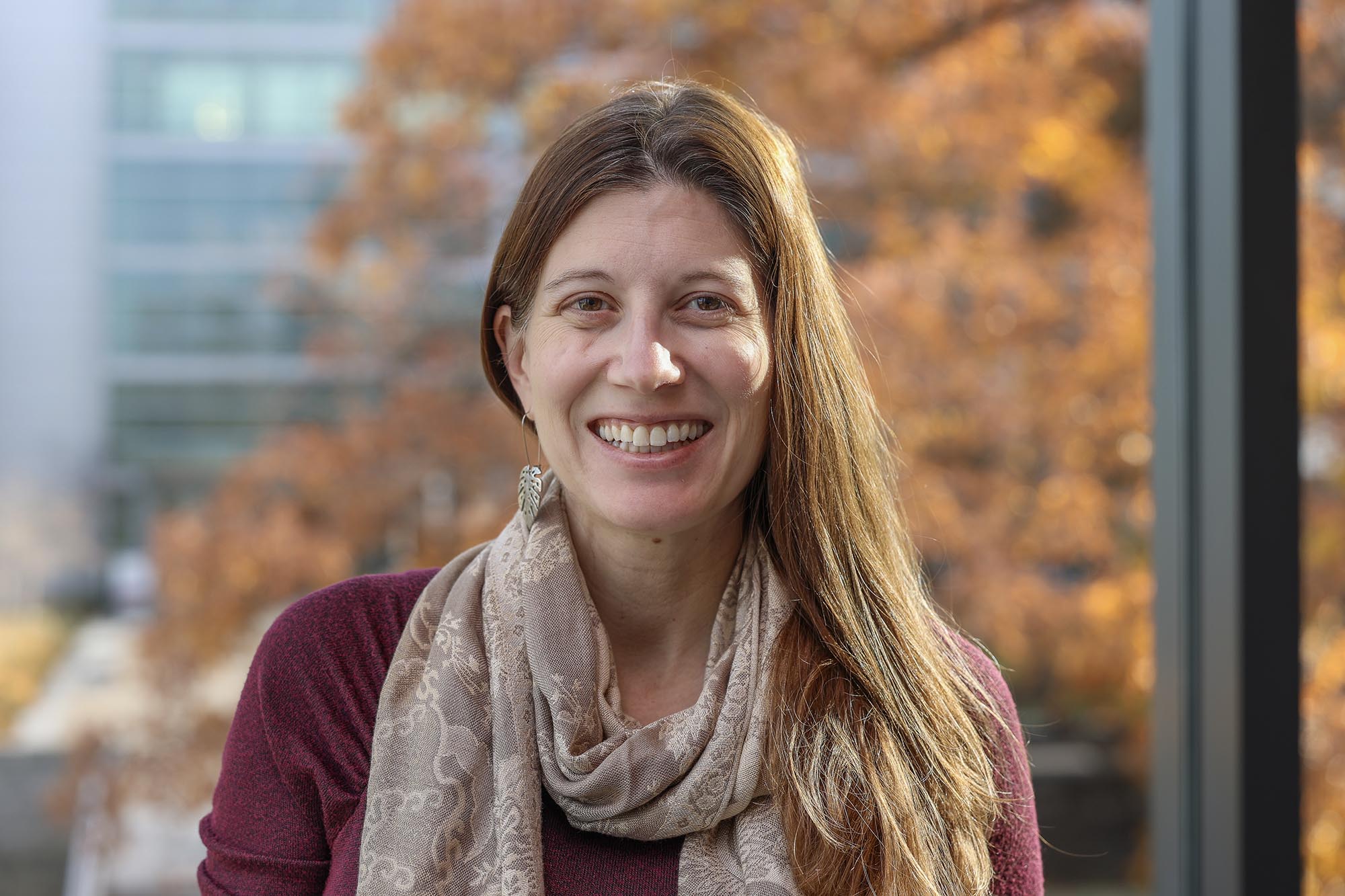 Alex Coso-Strong smiling inside with autumn leaves out of focus background