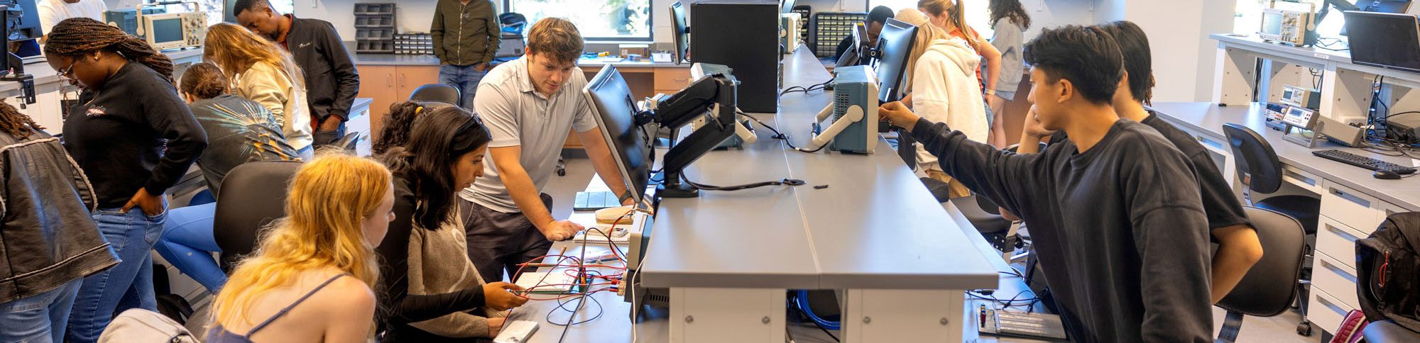 students work together in a lab with computers, monitors, and wires