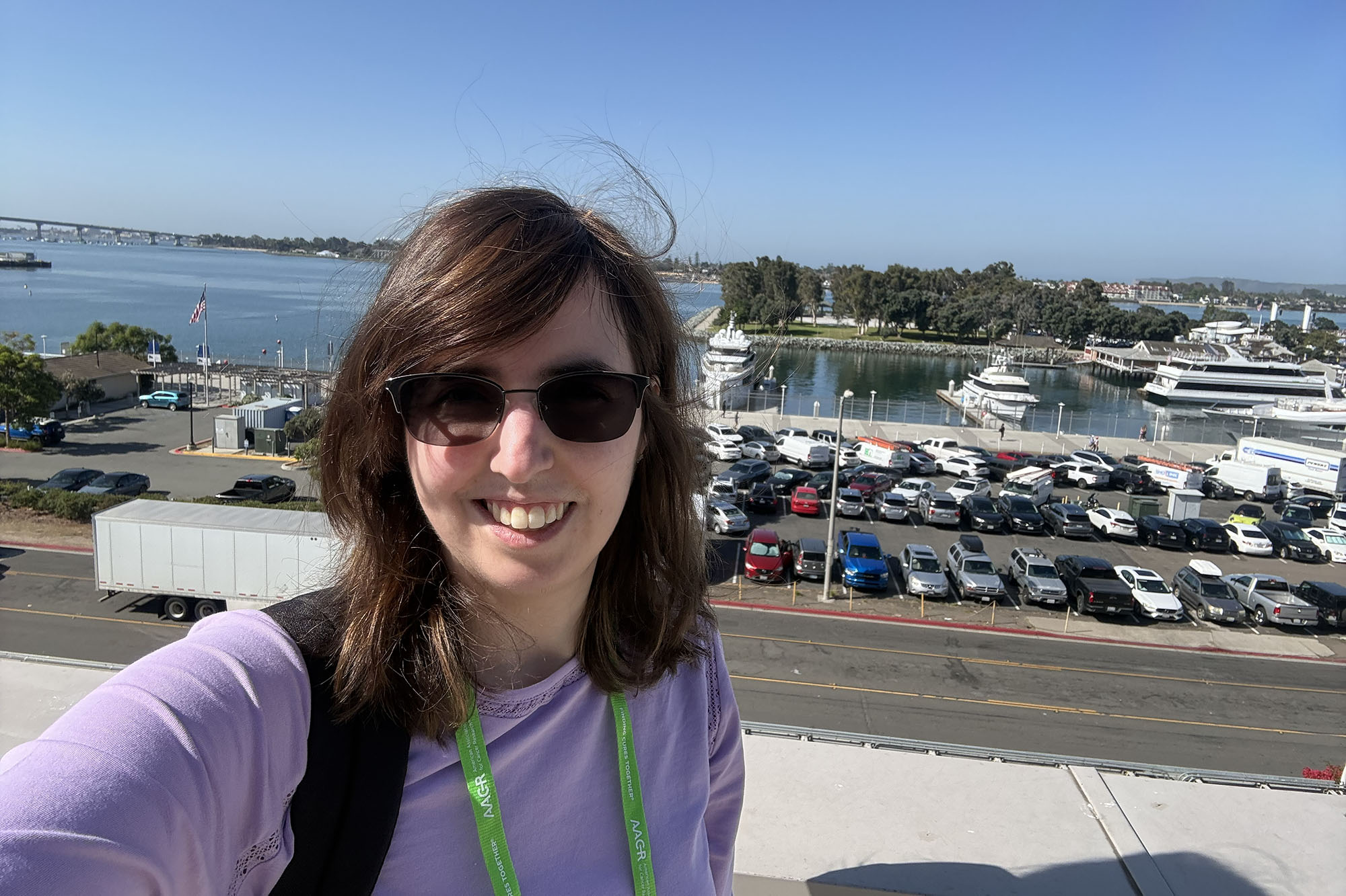 Michelle Walther self-portrait with parking lot and sea behind her attending the AACR conference in San Diego.