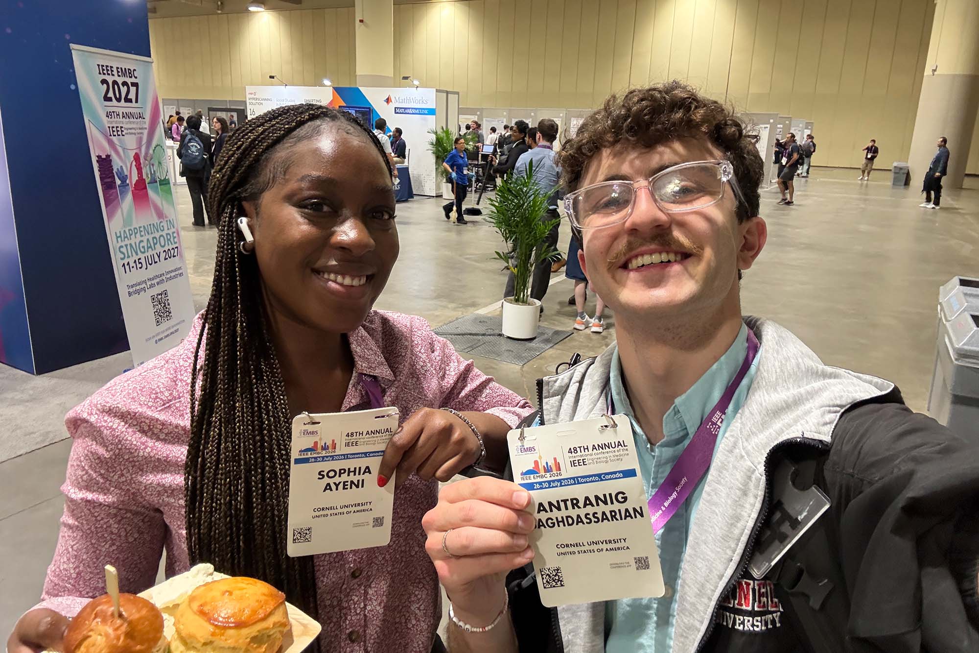 MEng student Sophia Ayeni and undergraduate student Antranig Baghdassarian smile at the at the Engineering in Medicine and Biology Conference (EMBC) conference exhibition hall in Toronto.